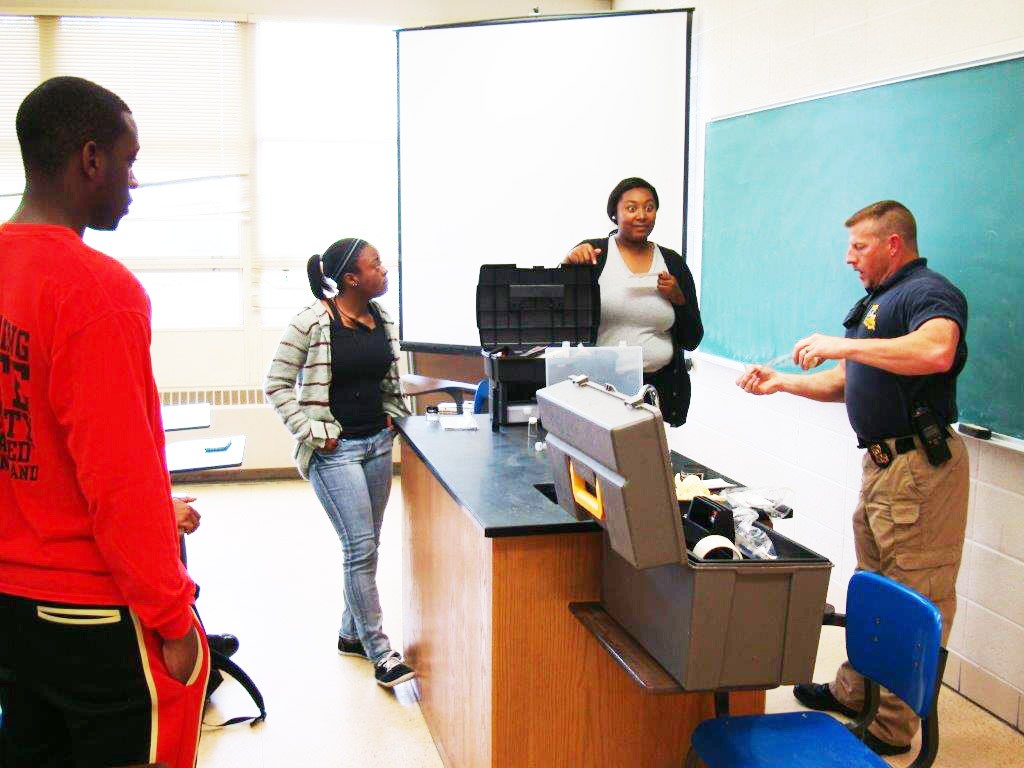 Courtesy photo Sgt. Rodney E. Pagans (right) explains some of the finer points of forensic chemistry to students Daniel Jolla, Shermaine Shorter and Taiylor Watts.