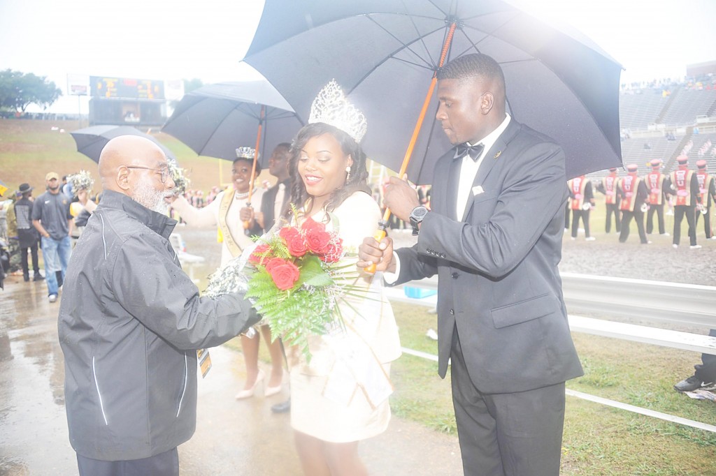 GLENN LEWIS/The Yearbook Miss GSU Joiya Smith receives flowers from President Willie Larkin as Desmond Stegall tries to hold the rain at bay.