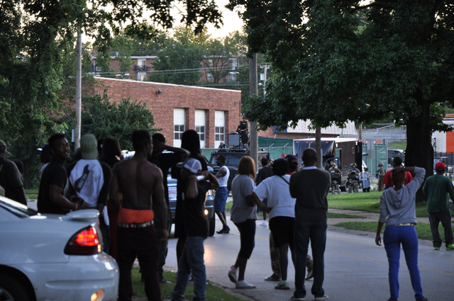 Protesters look on the SWAT barricade in Ferguson